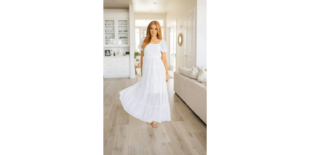 Woman in flowy white summer dress for curvy women standing in living room from Top 10 Summer Outfits for Curvy Women