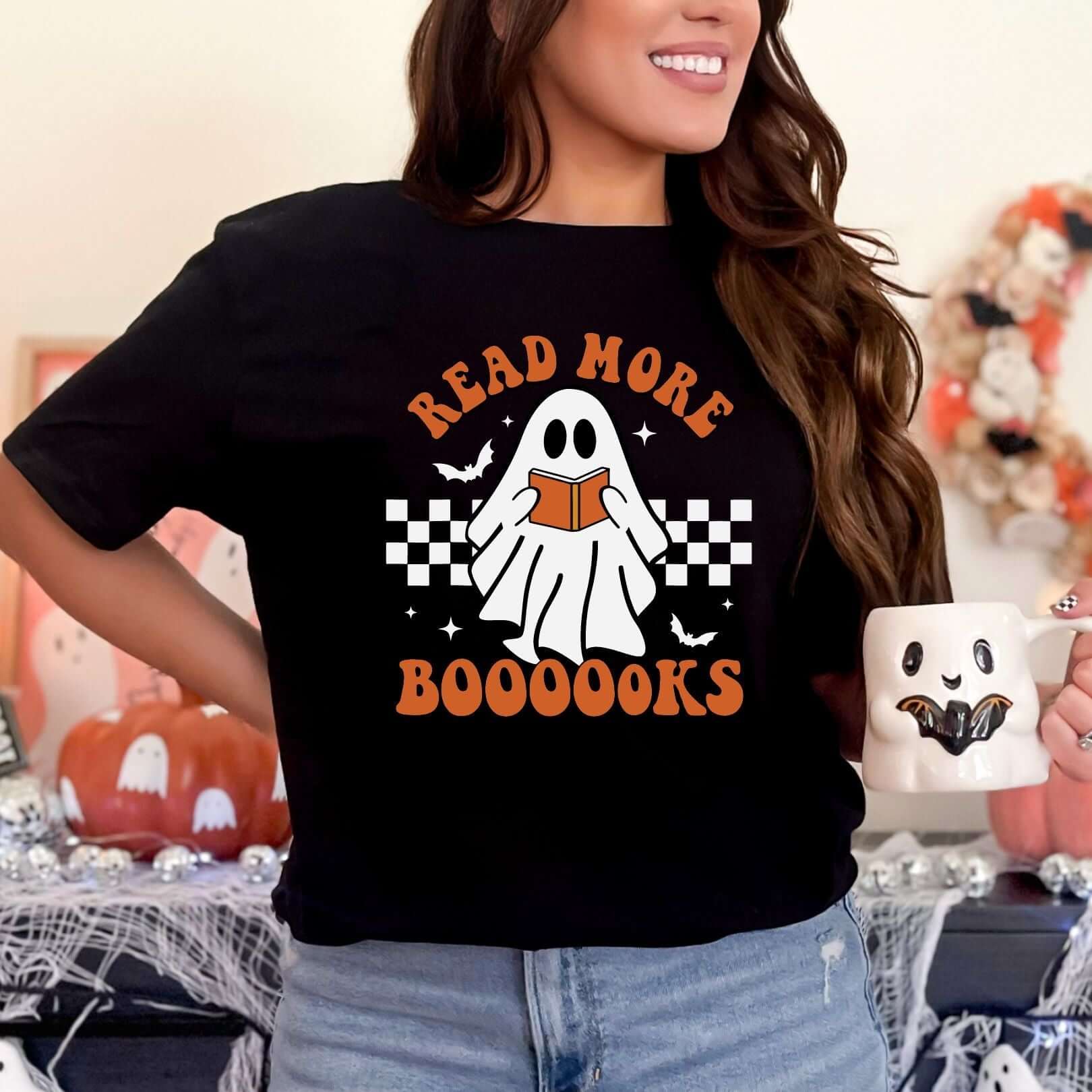 Woman wearing Read More Booooks graphic tee holding a Halloween-themed mug.