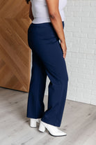 Woman wearing Magic Straight Pants in Navy, slim fit Ponte Knit fabric with elastic waistband, faux welt pockets, and white shoes