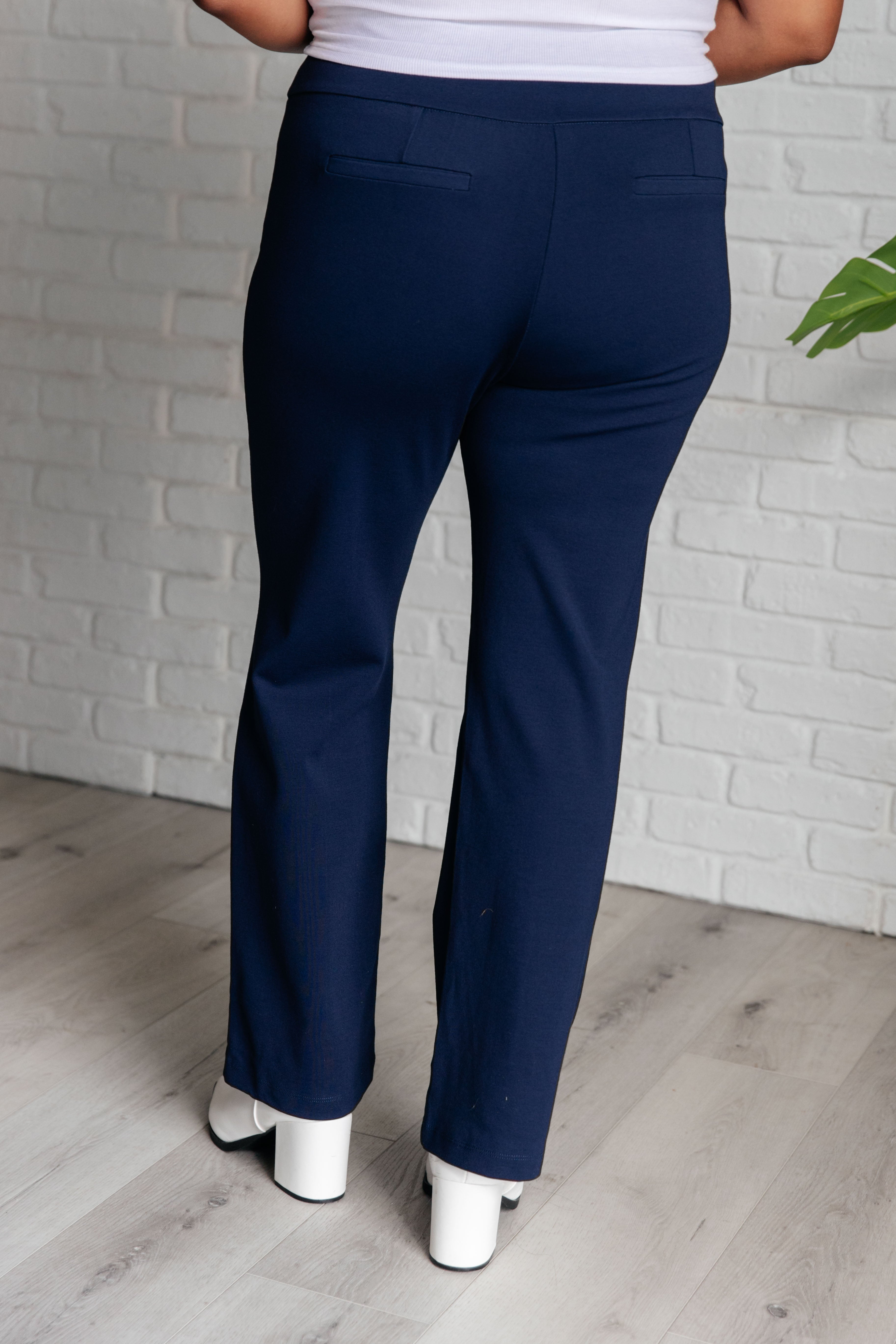 Back view of model wearing Magic Straight Pants in Navy, featuring faux welt pockets, straight leg silhouette, and vented hem.