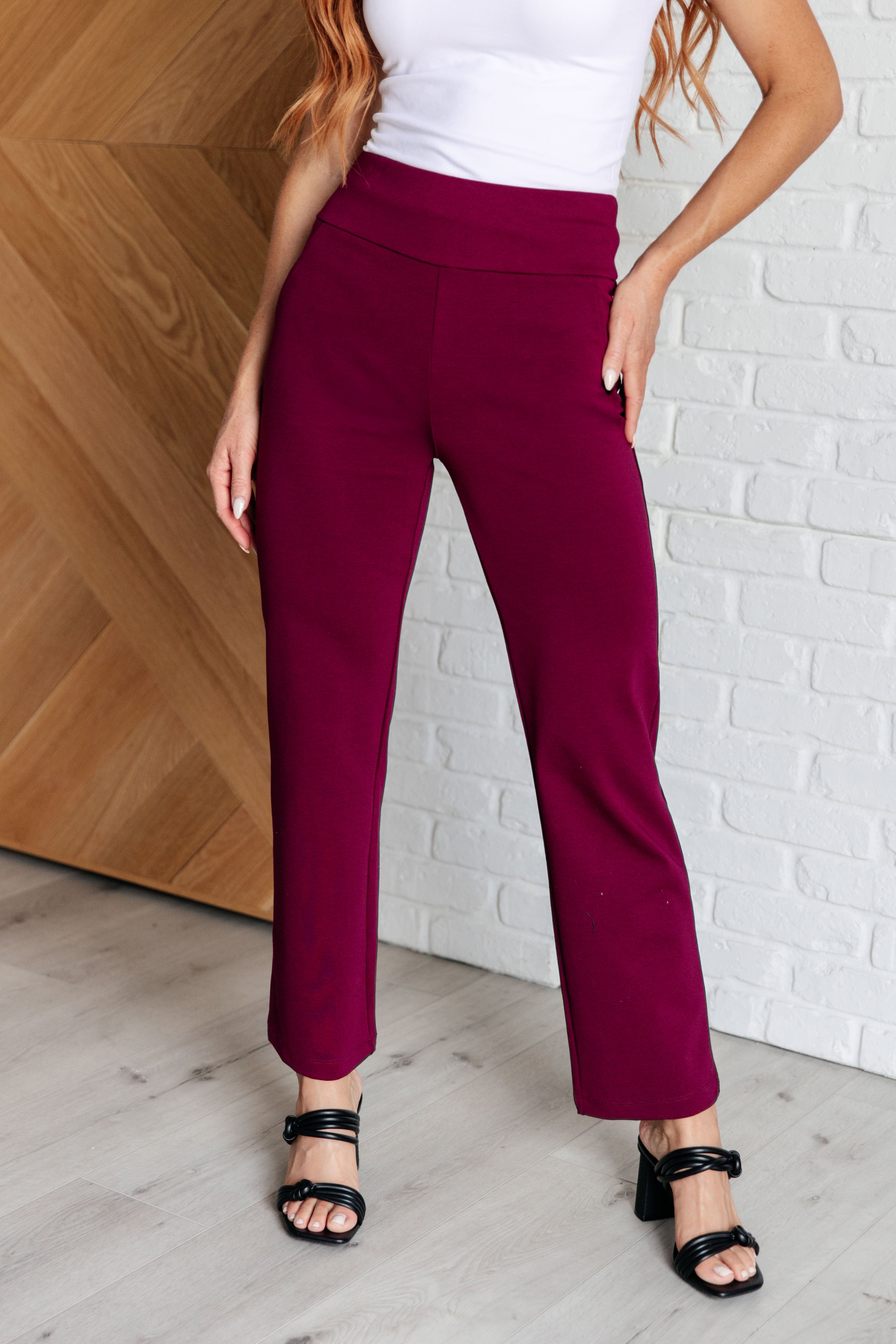 Woman wearing Magic Straight Pants in Wine with elastic waistband and faux welt pockets, showcasing slim fit and ankle crop design