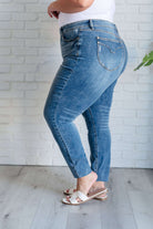 Nicole Tummy Control Skinny Jeans in Vintage Wash with high waist and decorative stitching, shown from the side against white brick wall.