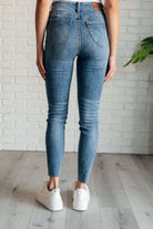 Nicole Tummy Control Skinny Jeans in vintage wash, back view, shown on model wearing white sneakers and standing against a white brick wall